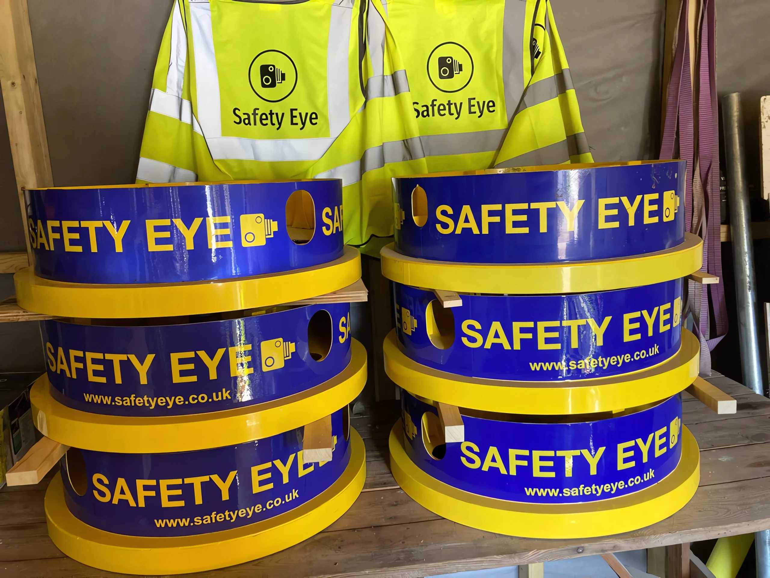 Safety Eye monitoring bollard units stacked with hi-vis vests showing product branding